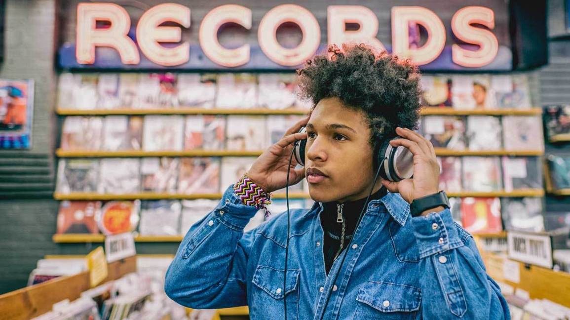 Teenage boy in record store listening to music